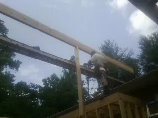 Carpenter setting a ridge beam over a new addition frame — Ice Dam Removal by Roofing Brothers in Falkville
