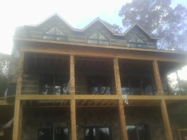 Dormers and porch framing on a large log home under construction — Roof Coating work by our crew in Falkville