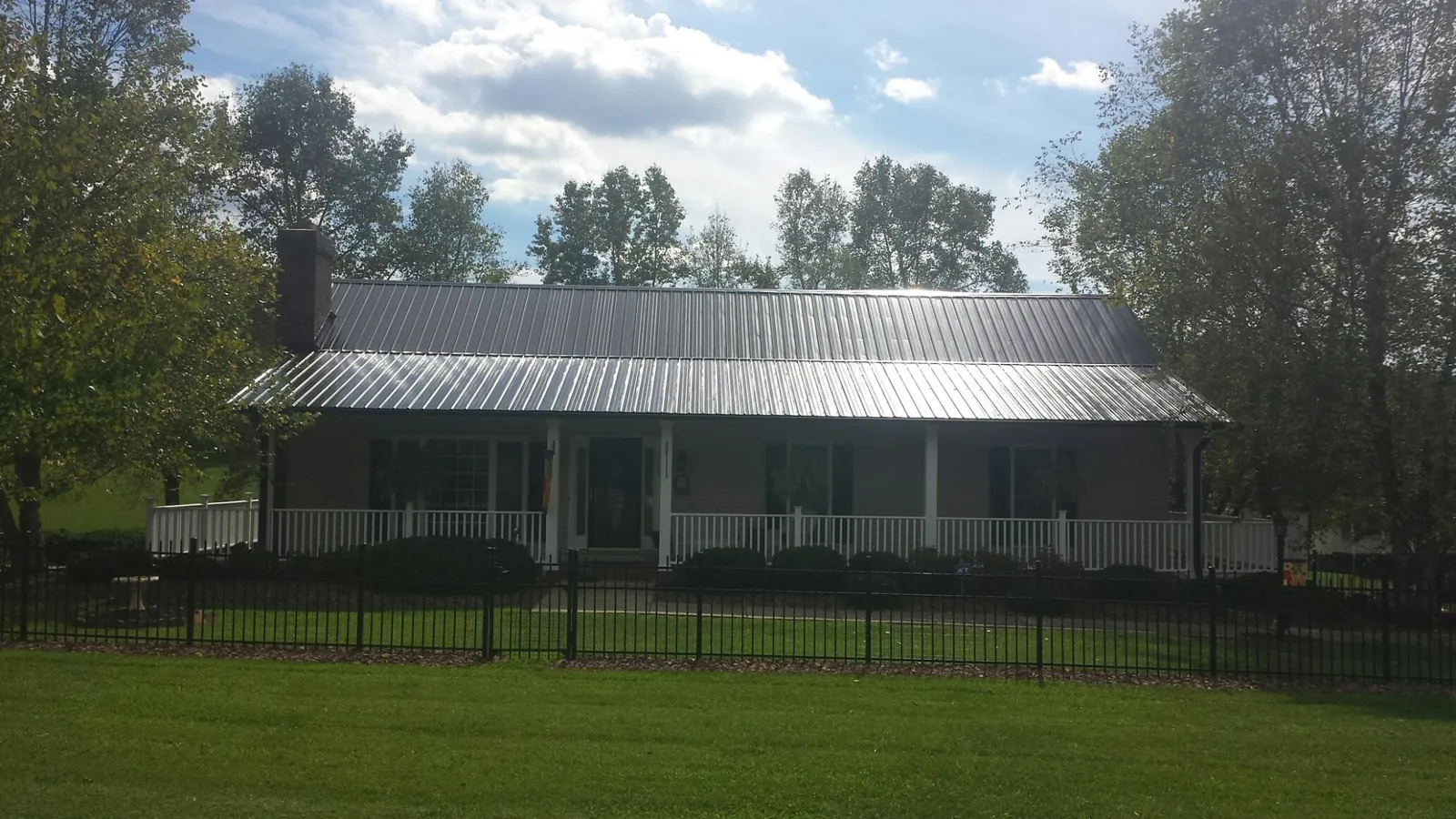 Gray metal roof on a brick ranch with a full width front porch — Gutter Guard Installation work by our crew in Falkville
