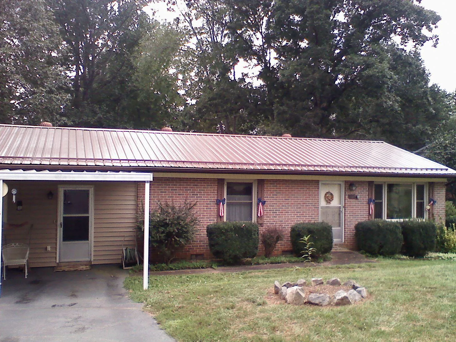 Bronze metal roof and carport on a brick ranch home — Roof Repair work by our crew in Falkville