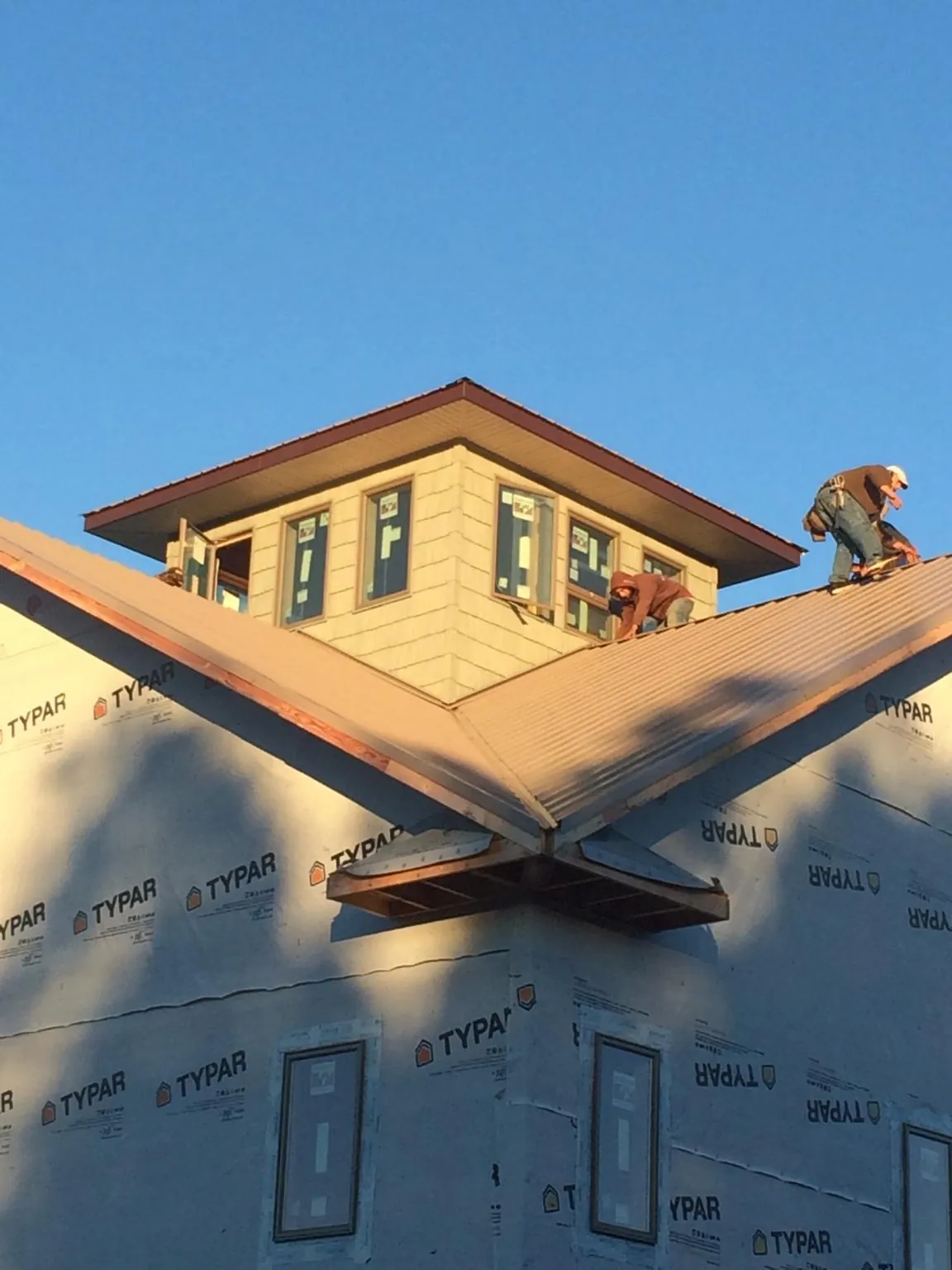 Roofers working around a rooftop cupola on a new metal roof at sunset — Roof Waterproofing in Falkville by Roofing Brothers